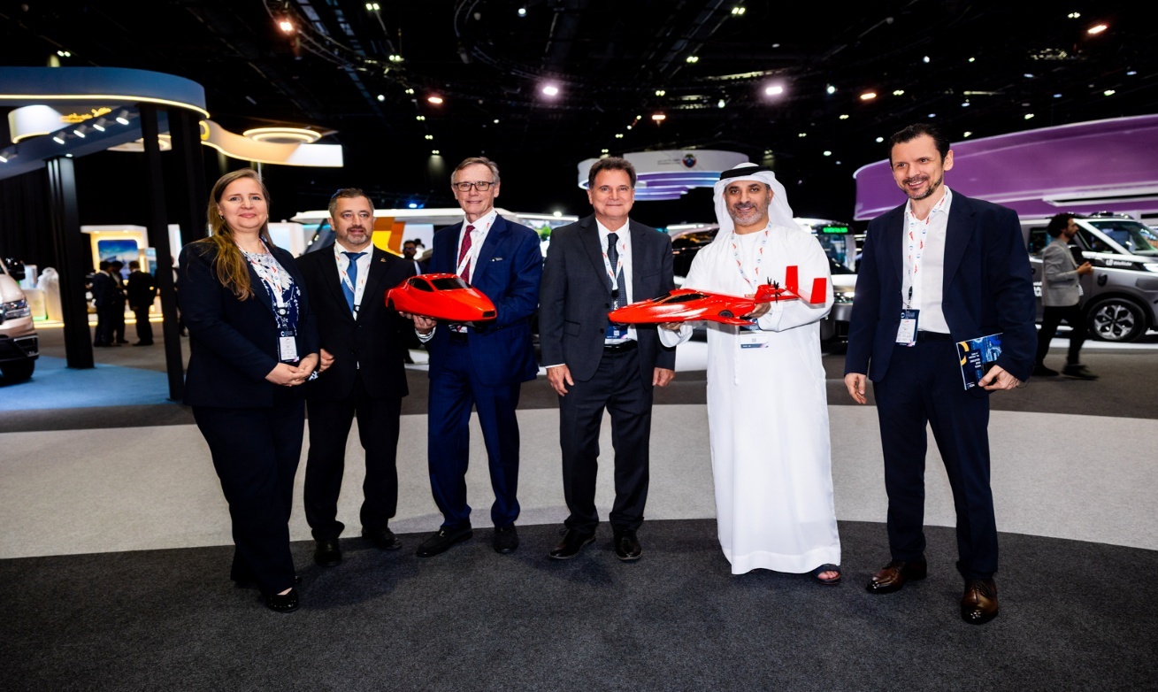 A group of well dressed people, some holding models of flying cars