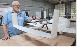 A man topuching a scale model of a flying car
