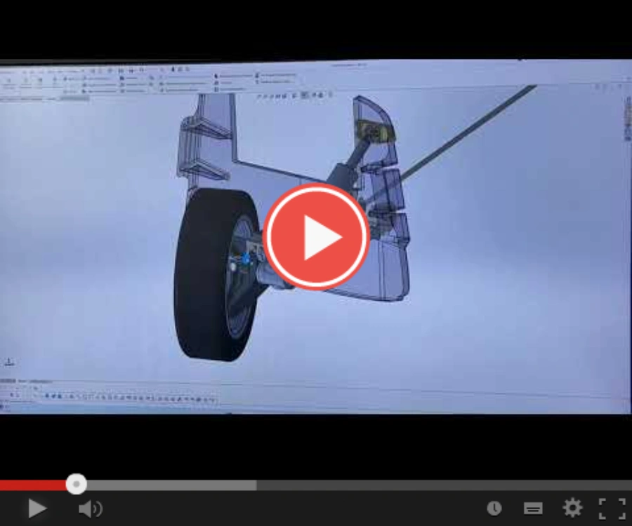 3D CAD model of a vehicle wheel and suspension on a computer screen, with a video play button.