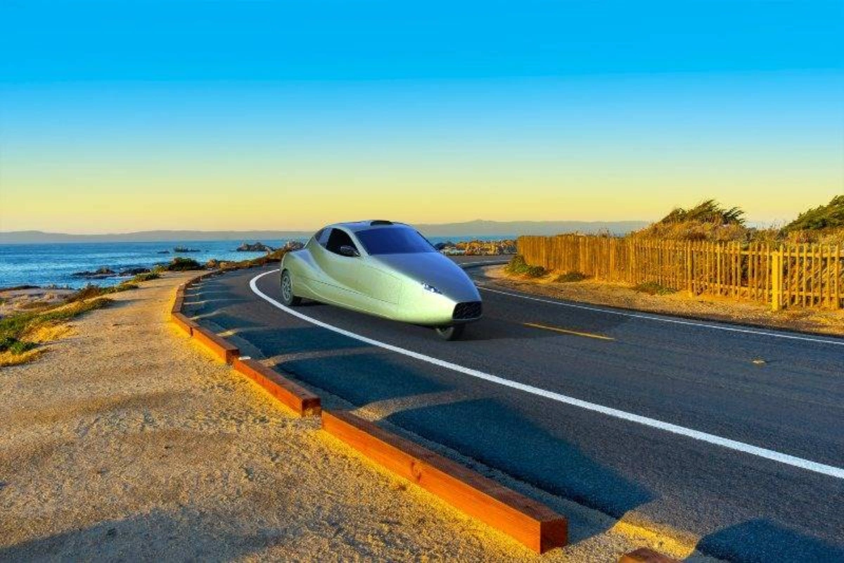 Sleek silver three-wheeled flying car driving on a scenic coastal highway at sunset.