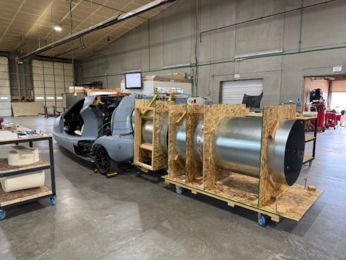 Prototype vehicle with large cylindrical exhaust system in a workshop.