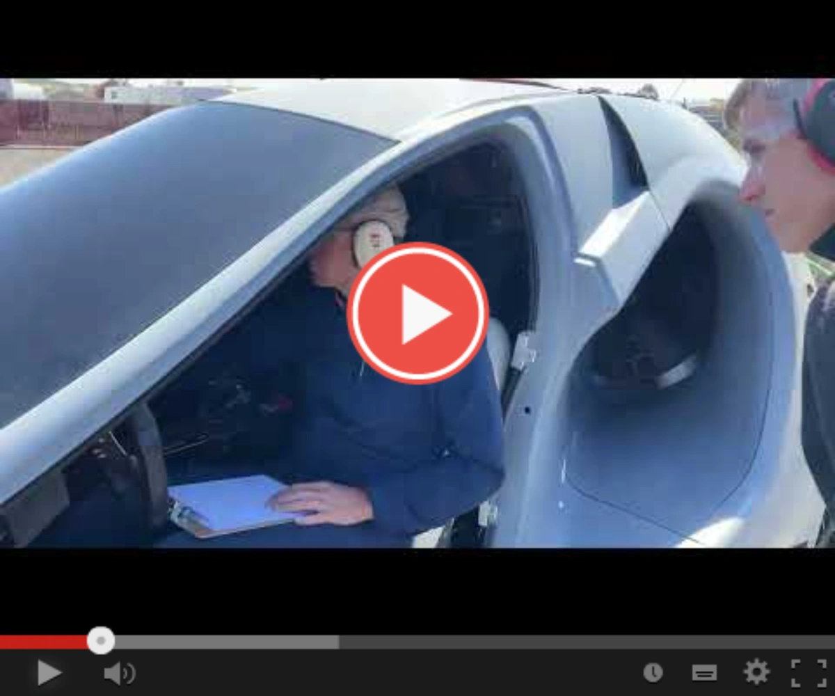 Pilot in futuristic vehicle with noise-canceling headphones and clipboard.
