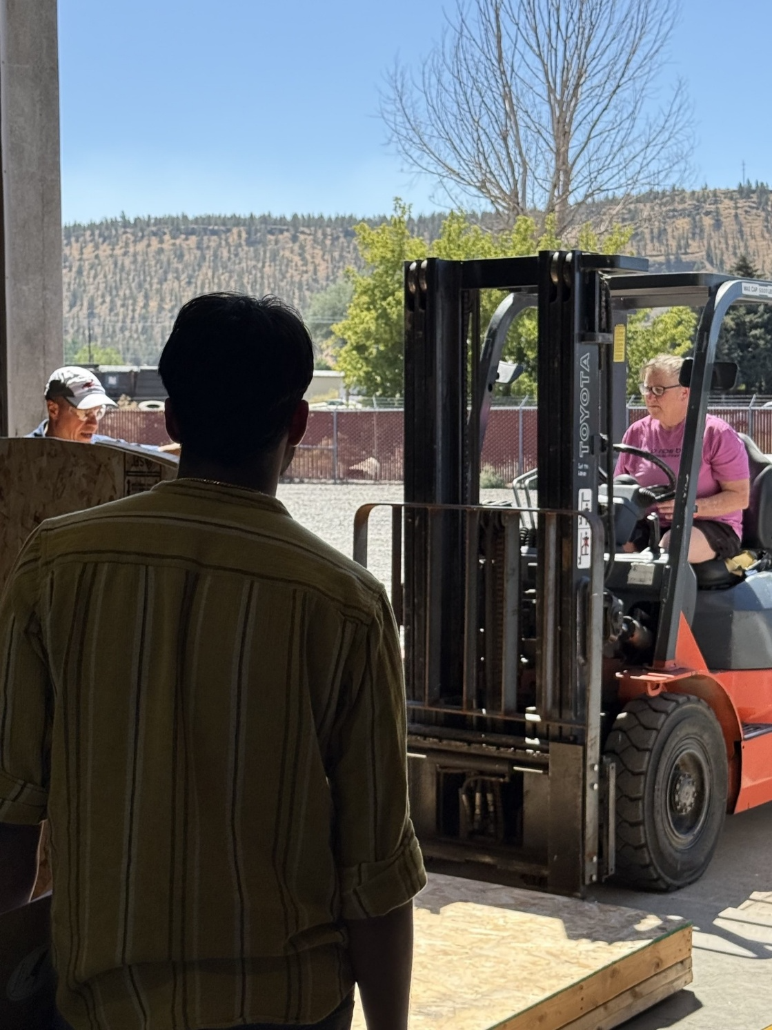Two men and a forklift in an outdoor industrial setting.