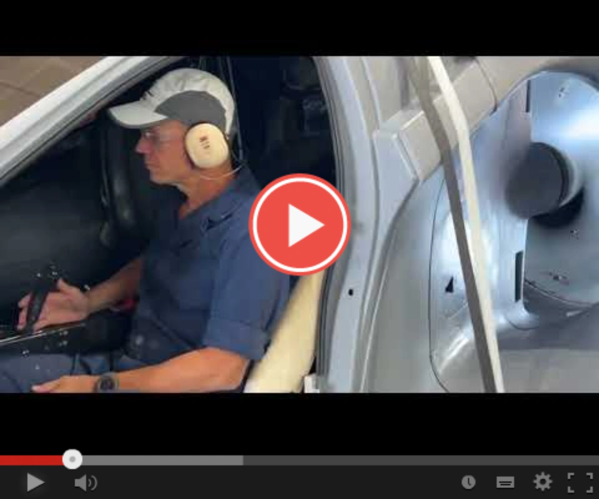 Man in car wearing headphones and a baseball cap, with a play button overlay.