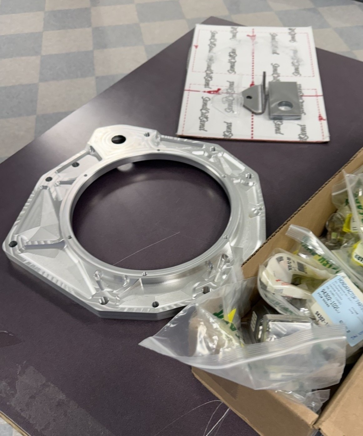 Machined aluminum transmission adapter plate and hardware in a box